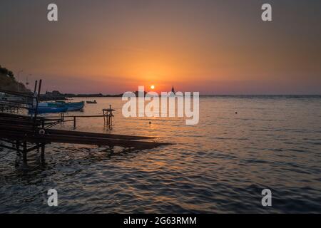 Ahtopol - 10. September: Sonnenaufgang am Strand mit Fischerpier, Felsen und Leuchtturm am 10. September 2016, Ahtopol, Bulgarien Stockfoto