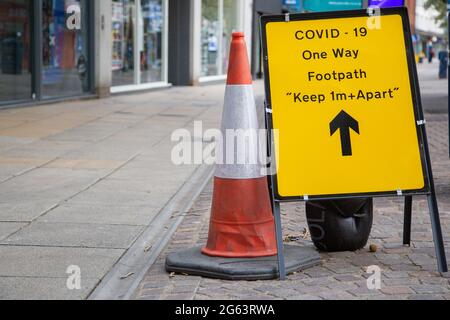 Ein Covid 19 Warnschild auf einer englischen Hauptstraße, das die Menschen warnt, während der Coronavirus-Pandemie auseinander zu bleiben Stockfoto
