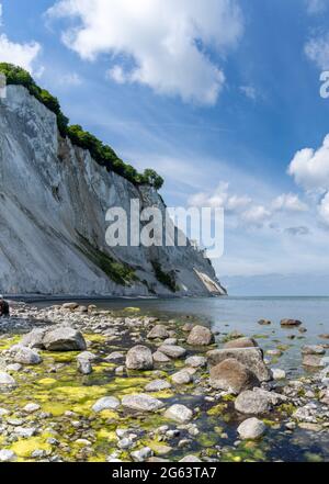 Ein vertikaler Blick auf den malerischen Ozean und die Küste mit ruhigem klarem Wasser und steilen weißen Kalksteinfelsen unter einem blauen Himmel mit weißen Cumuluswolken Stockfoto