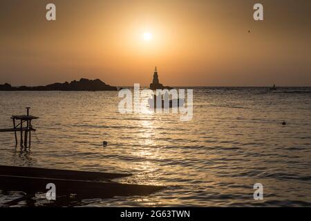 Ahtopol - September 10: Silhouette eines Bootes mit Fischern, die am 10. September 2016 bei Sonnenaufgang zwischen Felsen und Leuchtturm vom Fischfang zurückkehren, Ahtopol Stockfoto