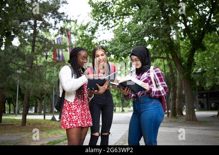 Junge multikulturelle Freunde unterhalten sich über einen Vortrag in ihrem Universitätspark Stockfoto