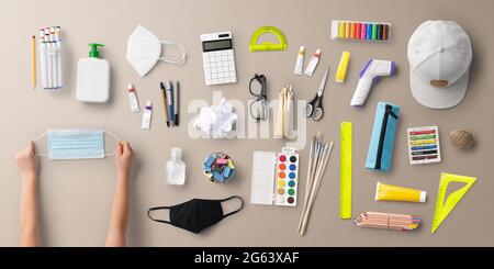 Flach Lay Draufsicht auf Gesichtsmaske und Schulbedarf, zurück zur Schule und Coronavirus Konzept. Stockfoto