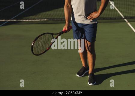 Mittelteil eines älteren afroamerikanischen Mannes mit Tennisschläger auf dem Tennisplatz Stockfoto