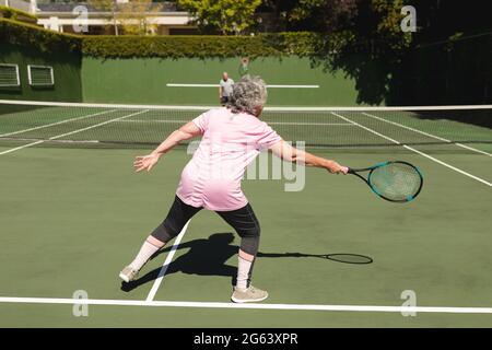 Ältere kaukasische Paare spielen gemeinsam Tennis auf dem Platz Stockfoto