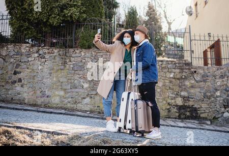 Junge Touristen mit Gepäck, die Selfie auf der Straße in der Altstadt machen, Coronavirus-Konzept. Stockfoto