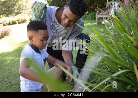 Glücklicher afroamerikanischer Vater mit Sohn im Freien, Gartenarbeit an sonnigen Tagen Stockfoto