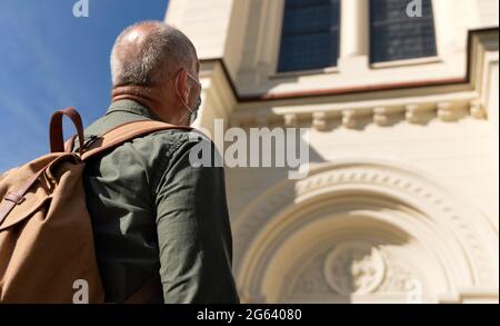 Rückansicht eines Touristen, der die Gesichtsmaske im Freien in der Stadt auszieht, Sehenswürdigkeiten. Stockfoto