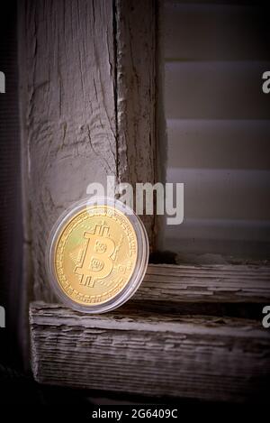 Bitcoin in einem Etui liegt auf einem alten Holzfensterrahmen. Dunkler Hintergrund Stockfoto