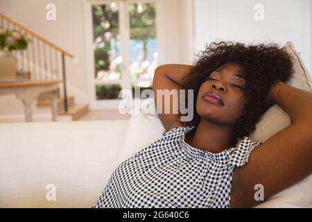 Porträt einer afroamerikanischen Frau mit geschlossenen Augen, die sich zu Hause auf dem Sofa zurücklehnen Stockfoto