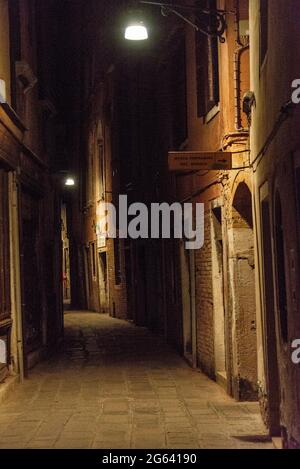 Eine schwach beleuchtete schmale Straße in Venedig, Italien Stockfoto