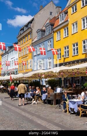 Kopenhagen, Dänemark - 13. Juni 2021: Die Menschen genießen einen Sommertag im geschäftigen Nyhavn-Viertel am Ufer in Kopenhagen mit vielen Restaurants und BA Stockfoto