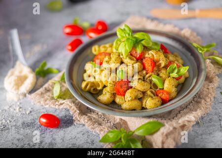 Basilikum-Pesto mit hausgemachter Pasta, gerösteten Tomaten und Parmesan Stockfoto