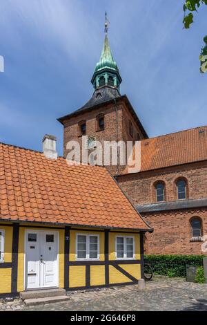 Svendborg, Dänemark - 10. Juni 2021: Rote Backsteinkirche und gelbes Fachwerkhaus in der historischen Altstadt von Svendborg Stockfoto