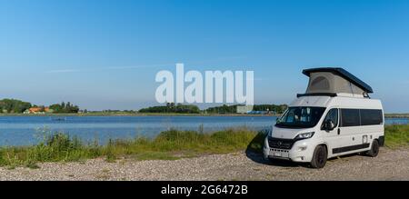 TARS, Dänemark - 10. Juni 2021- grauer Wohnmobil, der auf einer Schotterstraße am Meeresufer der Insel Lolland im Süden Dänemarks geparkt ist Stockfoto