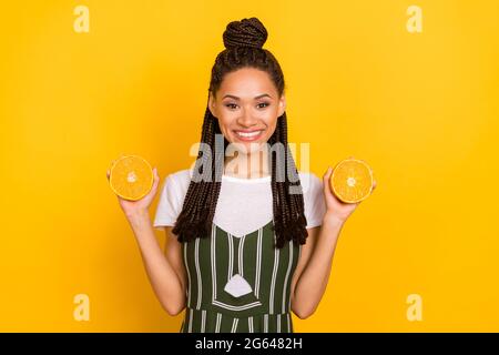 Foto von positiven schönen afro amerikanische junge Frau halten Hände Orangen isoliert auf gelbem Hintergrund Stockfoto