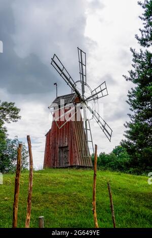 Gamla Uppsala, Schweden - 24. Juni 2021: Kleine rote Holzwindmühle auf einem grasbewachsenen Hügel auf dem Land Stockfoto