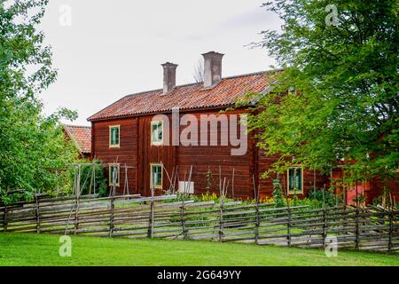 Gamla Uppsala, Schweden - 24. Juni 2021: Idyllische rote Ferienhäuser in der schwedischen Landschaft mit grünen Wiesen an einem schönen Sommertag Stockfoto