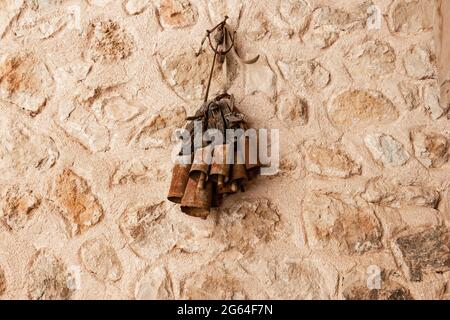 Rostige Kuhglocken für Rinder, die an einer Steinwand hängen Stockfoto