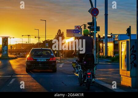 Berlin, Deutschland - 23. Juni 2021: Hinterleuchtete Fotografie einer Straßenkreuzung mit der glühenden Sonne im Hintergrund und den schattigen Fahrzeugen im for Stockfoto