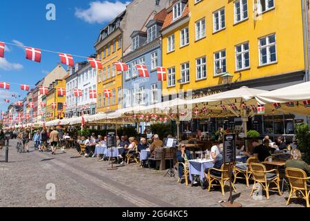 Kopenhagen, Dänemark - 13. Juni 2021: Die Menschen genießen einen Sommertag im geschäftigen Nyhavn-Viertel am Ufer in Kopenhagen mit vielen Restaurants und BA Stockfoto