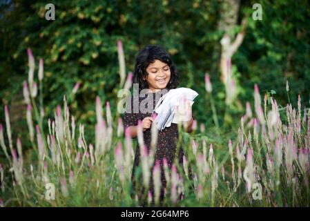 Asiatische Schulmädchen lesen ein Buch und spielen allein im Naturpark Stockfoto