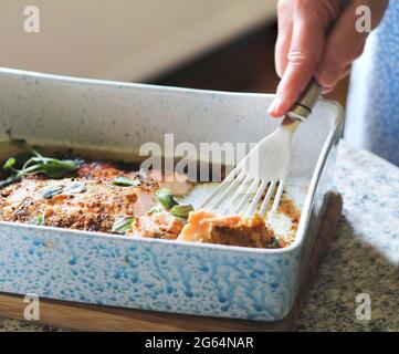 Frau, die zum Abendessen gebackenen Lachs mit Senf und Kräutern serviert Stockfoto