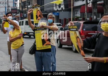 Vor seiner Beerdigung in Quezon City, Philippinen, versammeln sich Unterstützer neben der Autokolonne des ehemaligen philippinischen Präsidenten Benigno Aquino III. Stockfoto