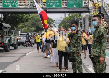 Vor seiner Beerdigung in Quezon City, Philippinen, versammeln sich Unterstützer neben der Autokolonne des ehemaligen philippinischen Präsidenten Benigno Aquino III. Stockfoto