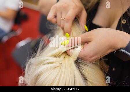 Die Hände der Frauen weben ein Zopf auf den Kopf der Brünette Stockfoto