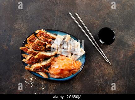 Heringsaal und Lachs auf schwarzem Teller, Fisch auf Teller Stockfoto