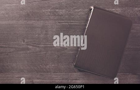 Eine einzelne schwarze Bibel auf einem schwarzen Holztisch Stockfoto