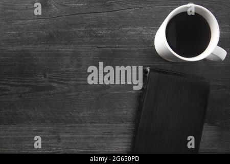 Eine einzelne schwarze Bibel auf einem schwarzen Holztisch Stockfoto