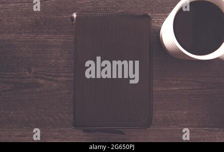 Eine einzelne schwarze Bibel auf einem schwarzen Holztisch Stockfoto