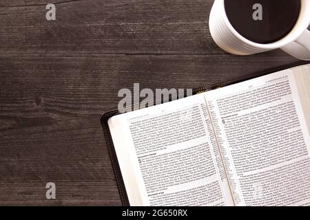 Eine einzelne schwarze Bibel auf einem schwarzen Holztisch Stockfoto