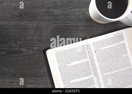 Eine einzelne schwarze Bibel auf einem schwarzen Holztisch Stockfoto