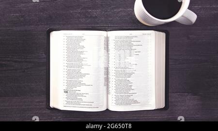 Eine einzelne schwarze Bibel auf einem schwarzen Holztisch Stockfoto