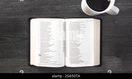 Eine einzelne schwarze Bibel auf einem schwarzen Holztisch Stockfoto