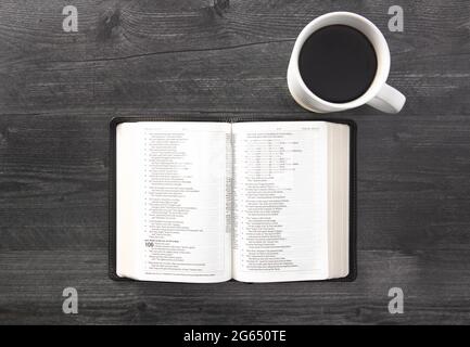 Eine einzelne schwarze Bibel auf einem schwarzen Holztisch Stockfoto