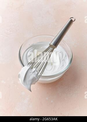 Schüssel mit geschlagenem Eiweiß auf rosa Hintergrund Stockfoto