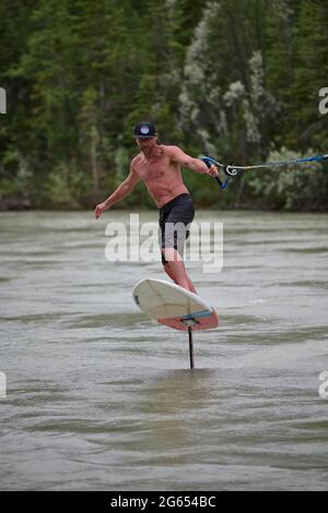 Todd Ril-Surfen (Foil Boarding) während des Flußes im Frühling im Bow River, Canmore, Alberta, Kanada. Stockfoto