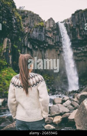 Island. Frau genießt majestätischen Svartifoss Wasserfall. Frau besucht berühmte Touristenattraktion von Island. Spektakuläres Naturdenkmal auf Stockfoto