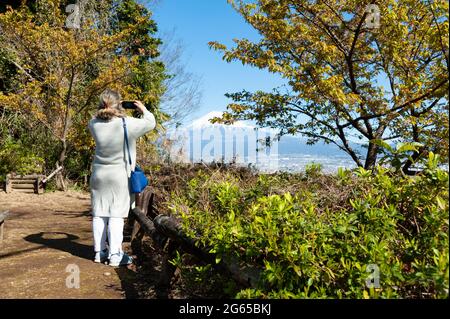 Frau, die an einem wunderschönen Wintermorgen ein Foto vom Berg Fuji mit Luftaufnahme der Stadt Fuji macht. Foto aufgenommen von Noroshiba, Kanbara, Shizuoka Ken. Stockfoto