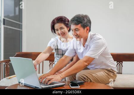 Mittleres Alter asiatisches Paar mit Laptop zu Hause Stockfoto