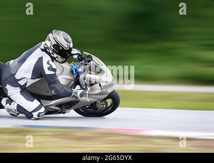 Motorrad-Praxis lehnt sich in eine schnelle Ecke auf der Strecke Stockfoto