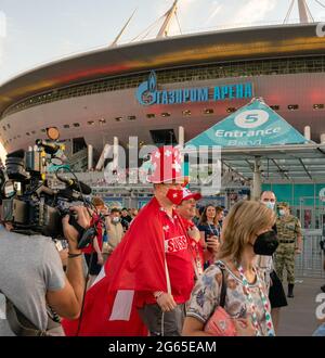 Schweizer Fußballfans in farbenfrohen Schweizer Outfits, eingewickelt mit Nationalflagge, mit Gesichtsmaske, spazieren in der Nähe der Gazprom Arena, St. Petersburg, Russland Stockfoto