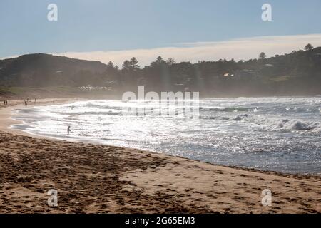 Am frühen Morgen geht die Sonne am Avalon Beach in Sydney unter, während Surfer zu den Wellen des Ozeans, NSW, Australien, fahren Stockfoto