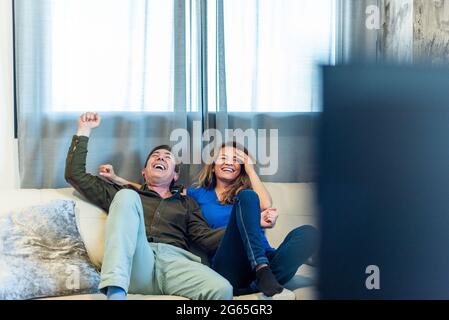 Reifes Paar feiert etwas, das sie im Fernsehen ansehen. Stockfoto