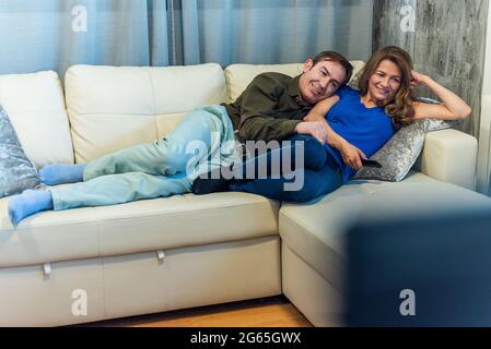 Reifer Mann und Frau liegen auf der Couch und schauen sich einen Film an. Stockfoto