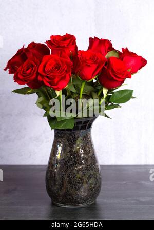 Ein Dutzend rote Rosen in einer Vase auf einem Holztisch Stockfoto