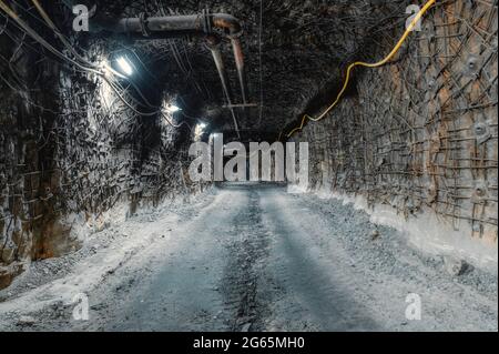 Unterirdische Mine. Unterirdische Straße für den Transport. Die Wände und die Decke des Tunnels sind mit Ankern und Metallgeflecht verstärkt Stockfoto